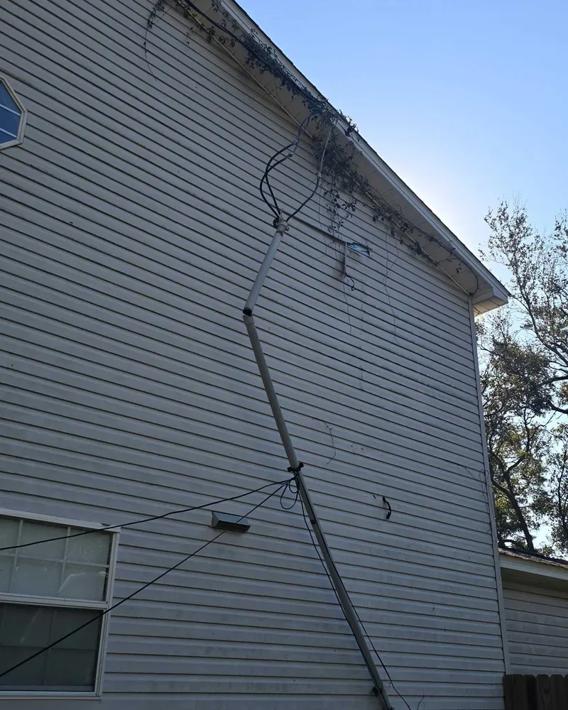 Electrical service mast pulled away from the siding of a two-story house after Hurricane Isaias