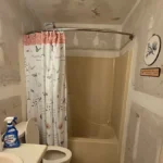 Unfinished bathroom renovation with stripped walls and a damaged ceiling in a Pensacola house we bought as-is