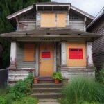 Boarded-up house in Everett WA with visible damage and a condemnation notice posted on the front door