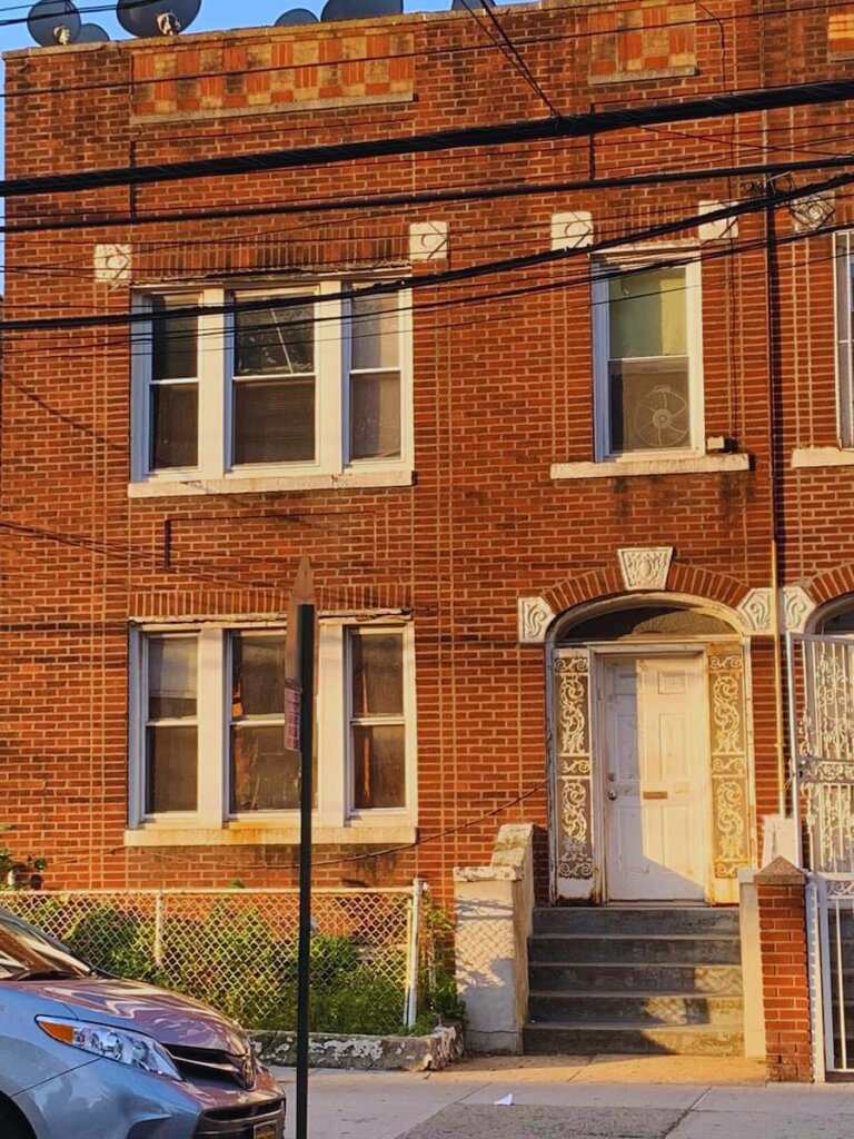 Brick row house in Hunts Point Bronx with ornate facade showing deferred maintenance — 718Homebuyers buys houses as-is for cash