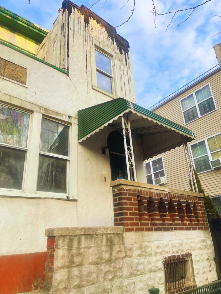 Distressed multi-family property in Melrose Bronx with deteriorating exterior and foundation damage — 718Homebuyers buys houses as-is for cash