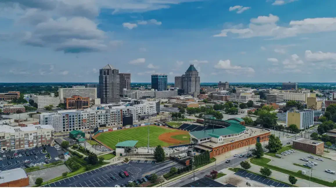 Aerial view of a city in Greensboro, NC, background image for Carolinas House Buyers website