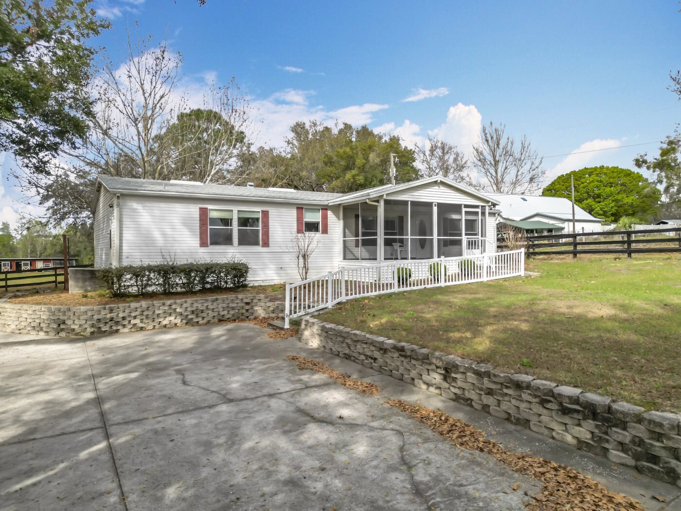 A mobile home listed by Florida Mobile Home Solutions in Apopka, Florida, with a screened porch and fenced yard