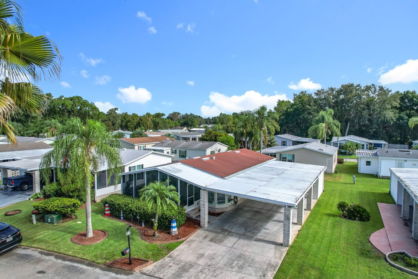 Aerial view of a mobile home in an Auburndale, Florida community, with a carport and screened porch
