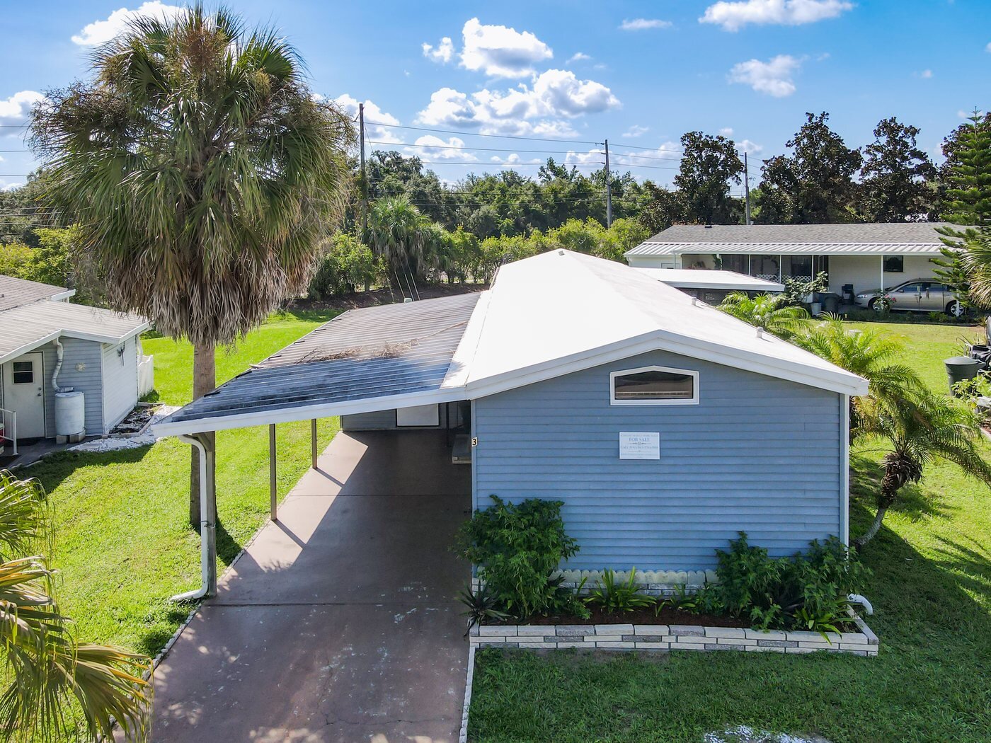 Aerial view of a mobile home in a Bartow, Florida community with a carport and mature trees
