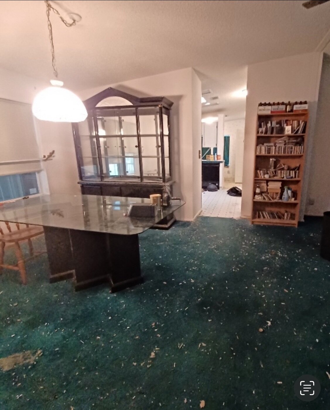 A dated Florida mobile home interior with old teal carpet and furniture left behind, ready to be cleared and sold