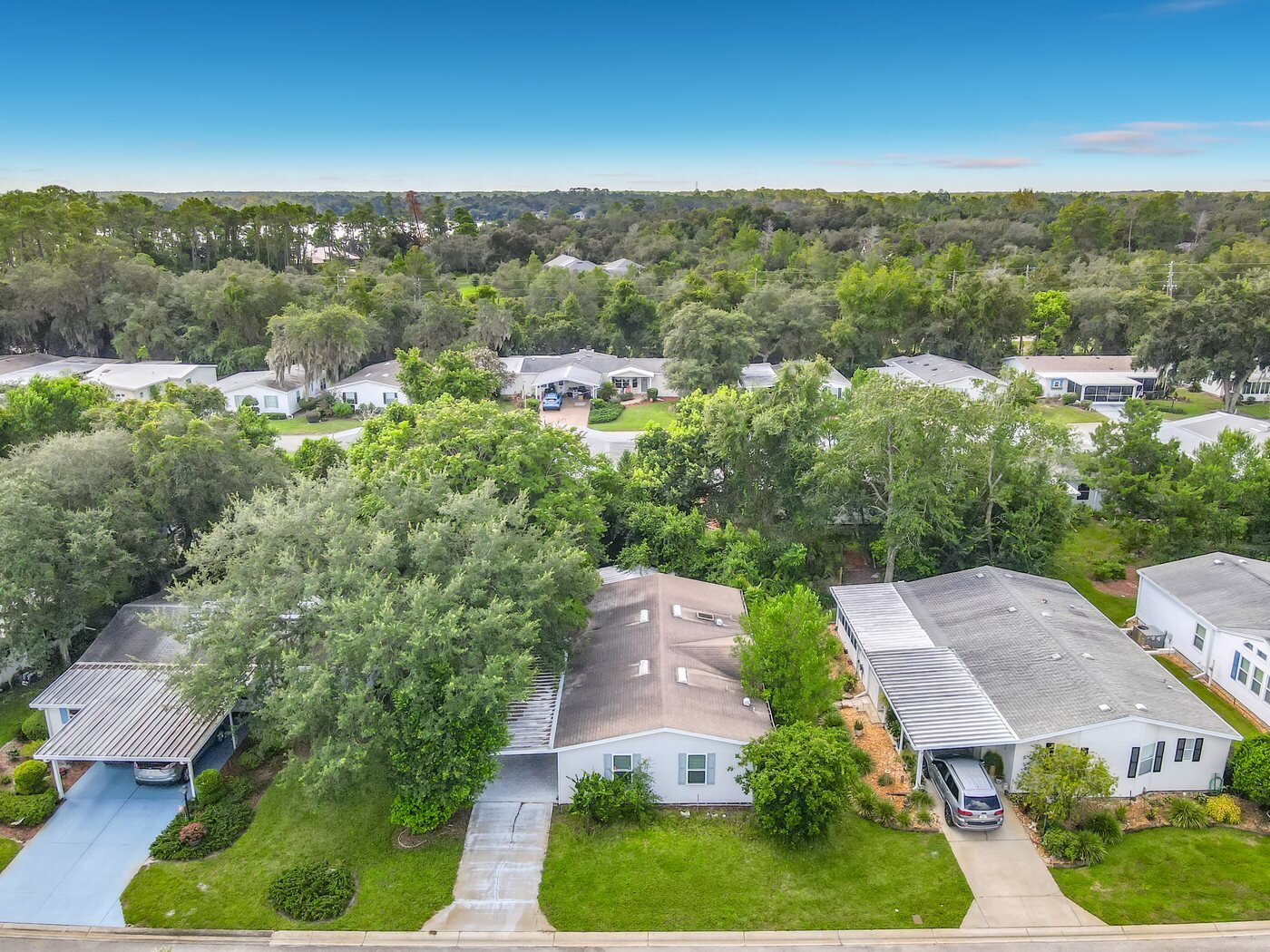 Aerial view of a mobile home community in DeLand, Florida, with tree-lined streets and single-story homes