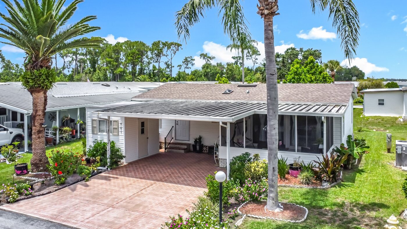 A mobile home listed by Florida Mobile Home Solutions in Haines City, Florida, with a carport and mature palms