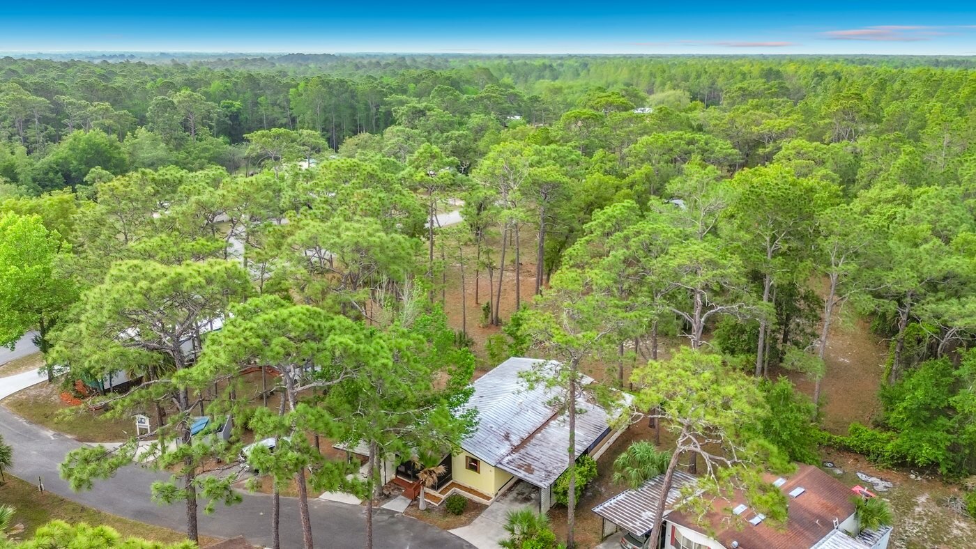 A mobile home listed by Florida Mobile Home Solutions in Homosassa, Florida, on a wooded lot with mature trees