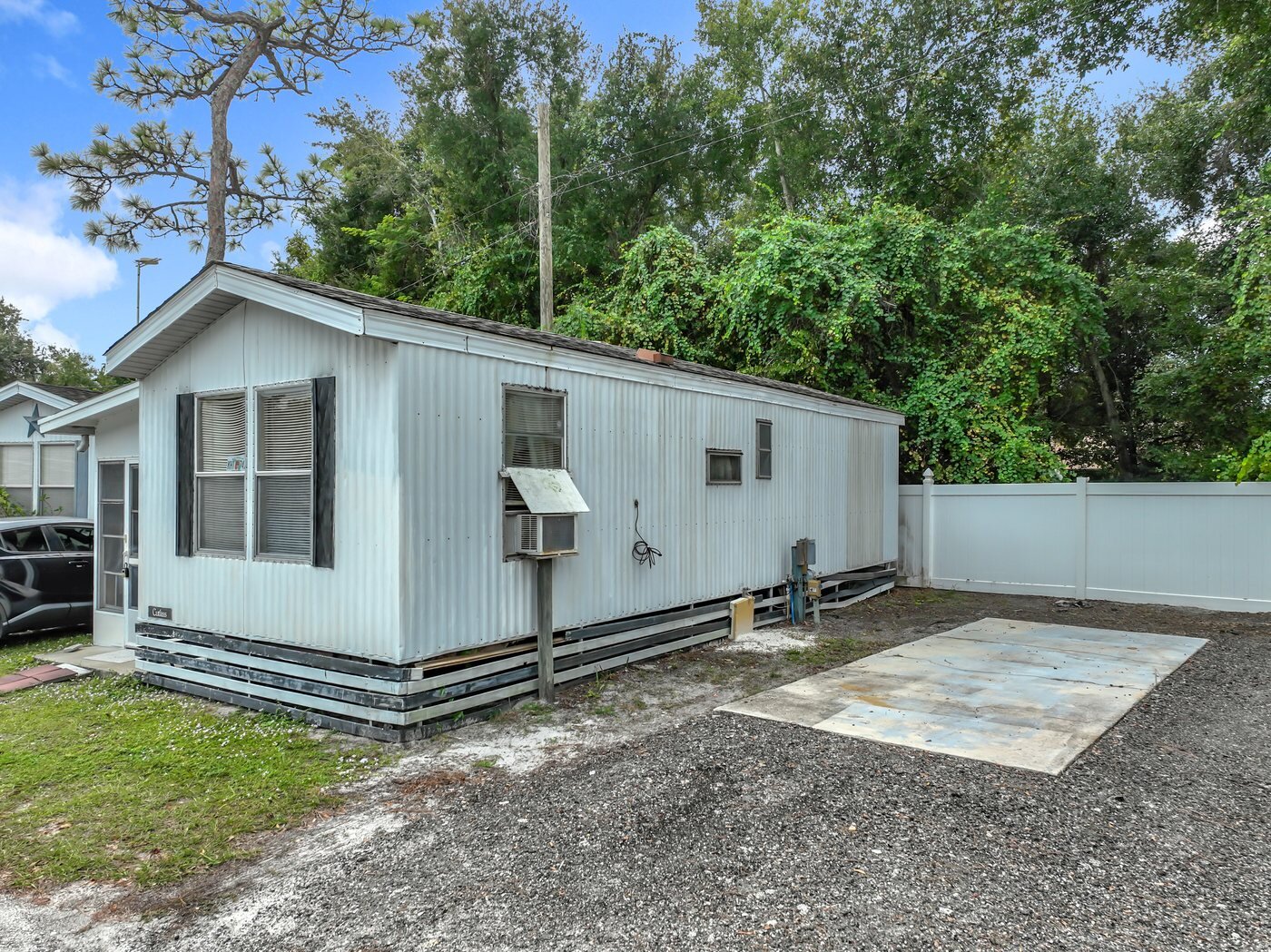 A mobile home listed by Florida Mobile Home Solutions in Kissimmee, Florida, with a carport and paved drive