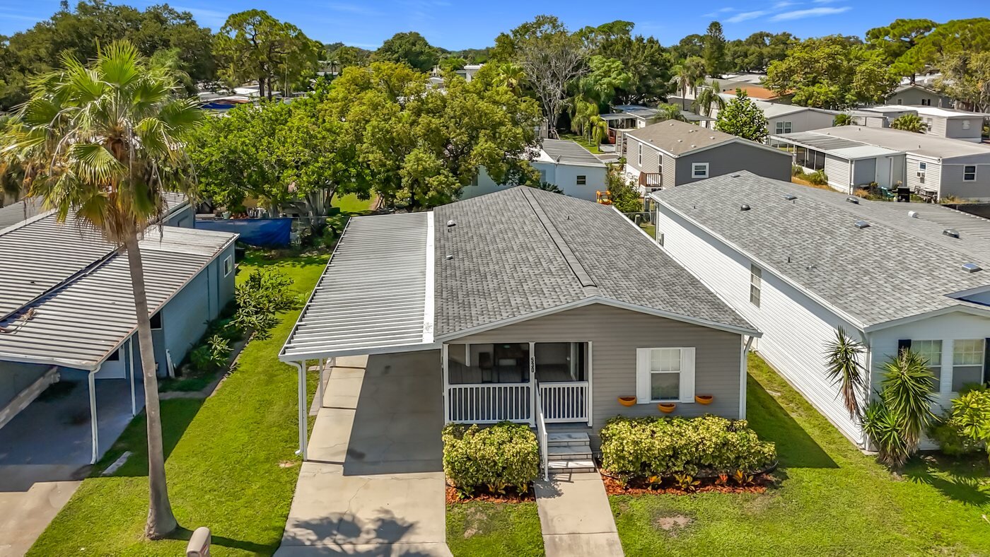 A mobile home listed by Florida Mobile Home Solutions in Largo, Florida, with a screened porch and covered parking