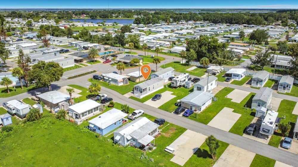 Drone photo of a Florida mobile home community with the listed home marked, showing the lake and surrounding streets