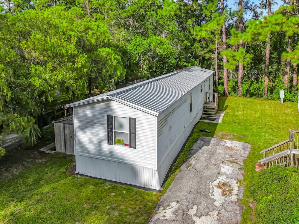Drone photo of a single wide mobile home on a private wooded lot in Florida