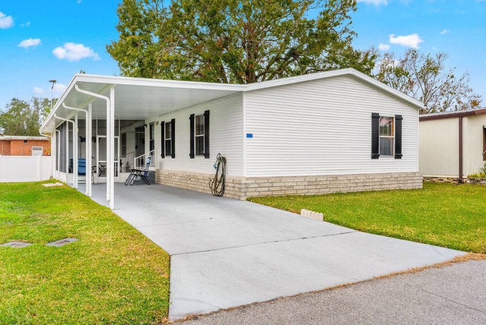 Florida mobile home with screened porch, block skirting and a wide concrete drive, professionally photographed for listing