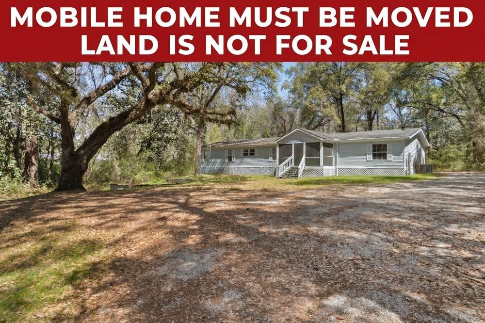 Mobile home with a screened porch under oak trees, listed as must be moved with the land not for sale