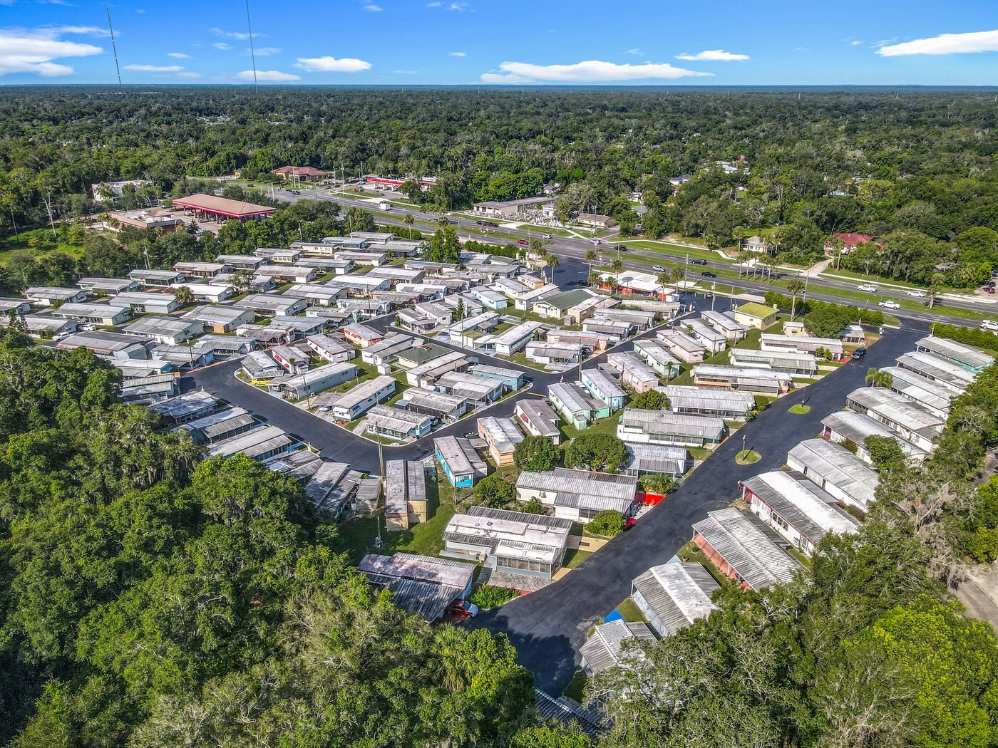 Aerial view of a mobile home in an Orange City, Florida community, with a carport and mature oaks