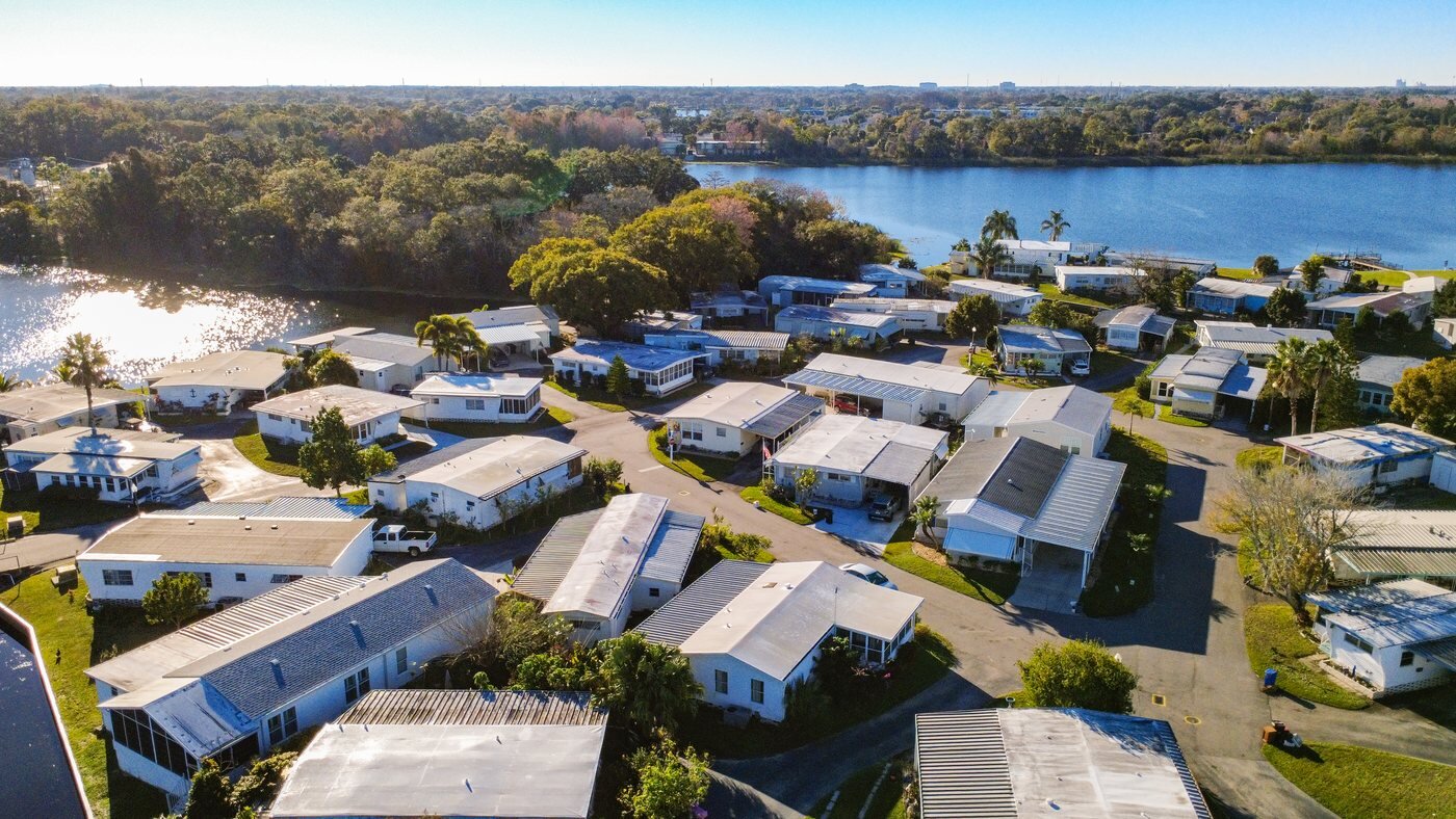 Aerial view of a mobile home community in Orlando, Florida, beside a lake with paved streets and mature landscaping