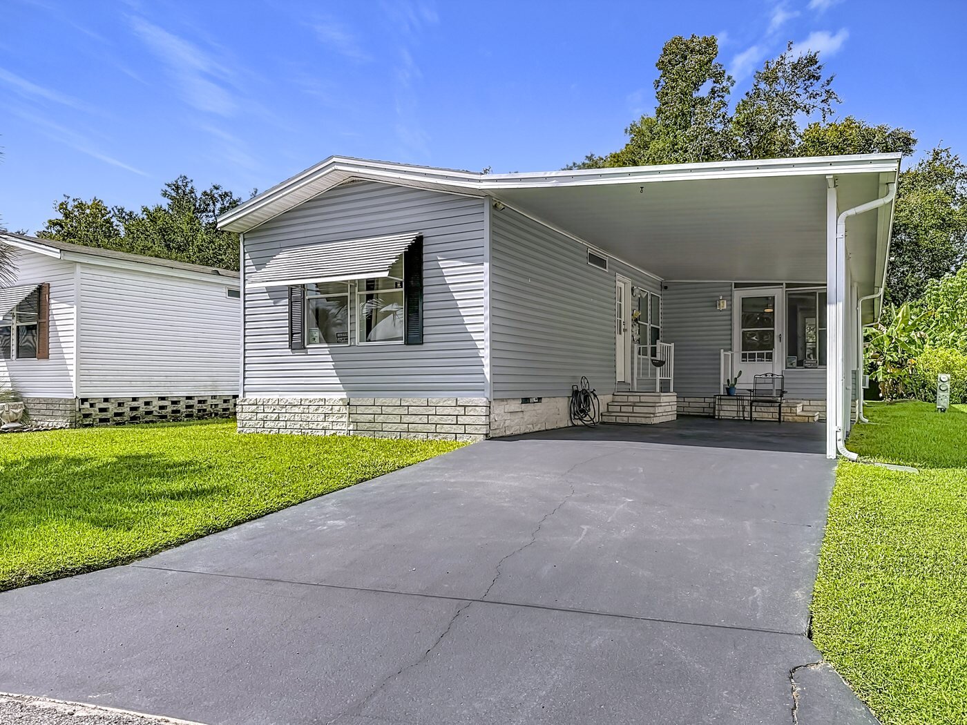 A mobile home listed by Florida Mobile Home Solutions in Plant City, Florida, with a carport and a paved drive