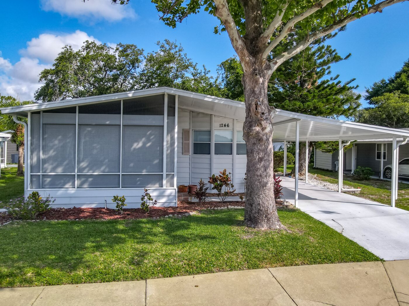 A mobile home listed by Florida Mobile Home Solutions in Port Orange, Florida, with a screened lanai and covered carport