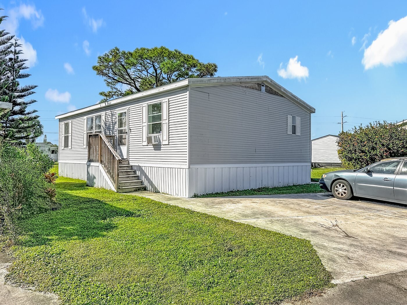 A mobile home listed by Florida Mobile Home Solutions in Stuart, Florida, with a covered carport and paved drive