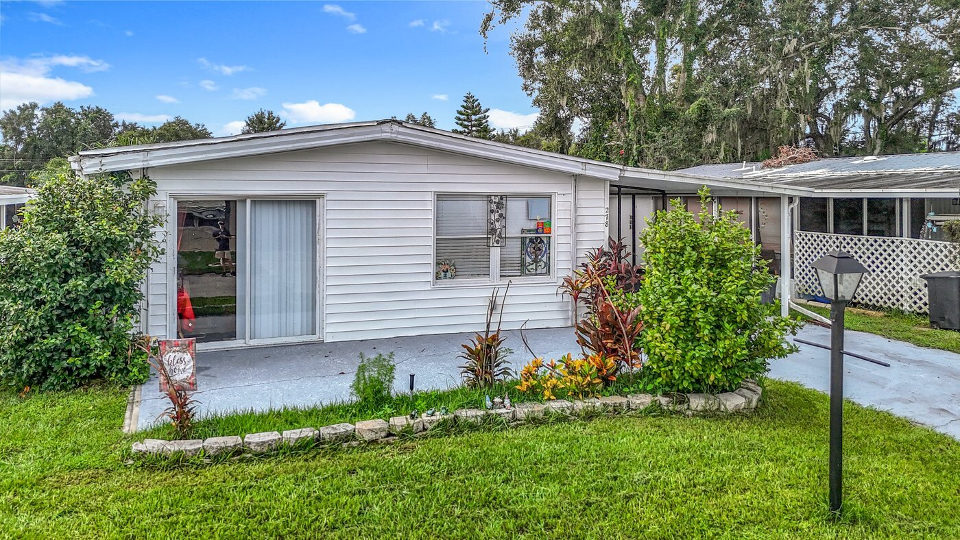 Aerial view of a mobile home in a Valrico, Florida community with a carport and screened porch