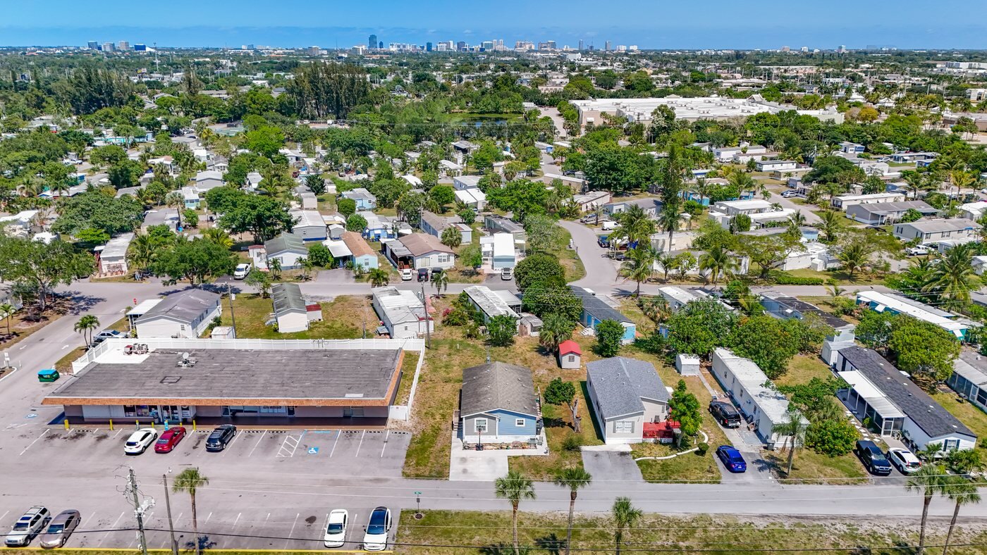 A mobile home listed by Florida Mobile Home Solutions in West Palm Beach, Florida, in a community with mature landscaping