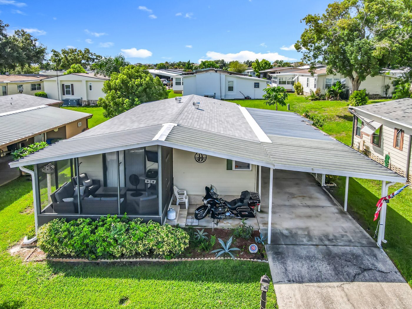 Aerial view of a mobile home in a Winter Haven, Florida community with mature landscaping and a screened porch