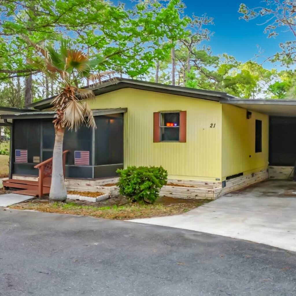 Yellow Florida mobile home with carport and palm tree, bought for cash as-is by Florida Mobile Home Solutions