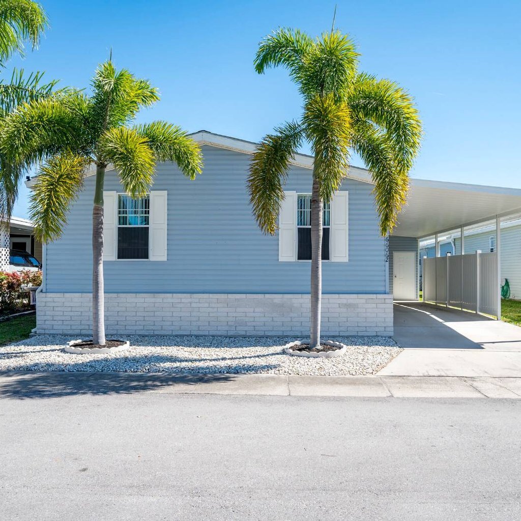 Florida mobile home with palm trees and a carport, listed for sale by a licensed Florida mobile home broker