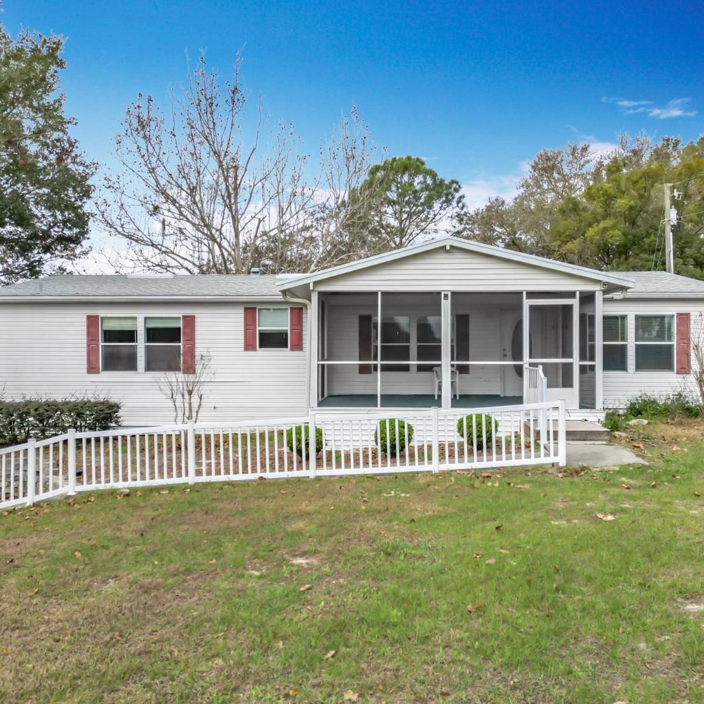 Florida mobile home with a screened porch and white fence, bought for cash as-is by Florida Mobile Home Solutions
