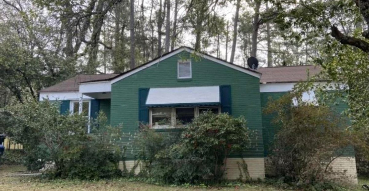 Older green Greenville, SC house with overgrown landscaping, before Peak Home Buyers bought it as-is
