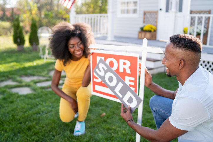 black-couple-with-a-for-sale-sign-on-their-front-yard