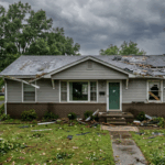 A residential home in Clarksville Tennessee with visible roof storm damage and broken windows, showing hail dents and missing shingles, representing a property eligible for cash sale