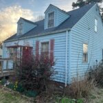 An exterior view of a damaged house for sale.