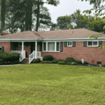 A house in Virginia Beach with gabled roofs, brick siding, and a mowed lawn bought by HR Property Doctor- Cash Home Buyers of real estate in Virginia.