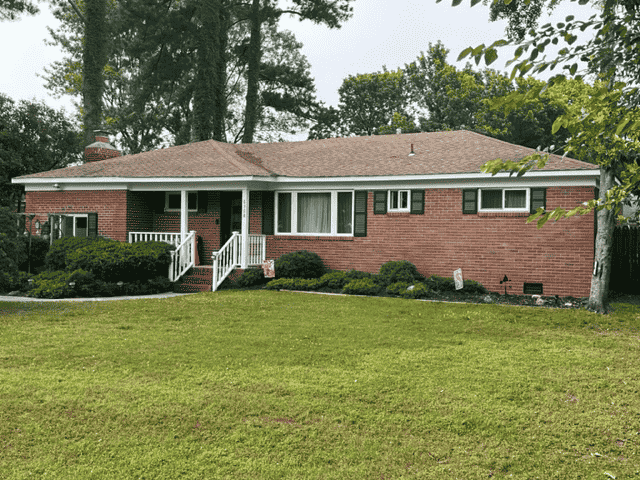 A house in Virginia Beach with gabled roofs, brick siding, and a mowed lawn bought by HR Property Doctor- Cash Home Buyers of real estate in Virginia.