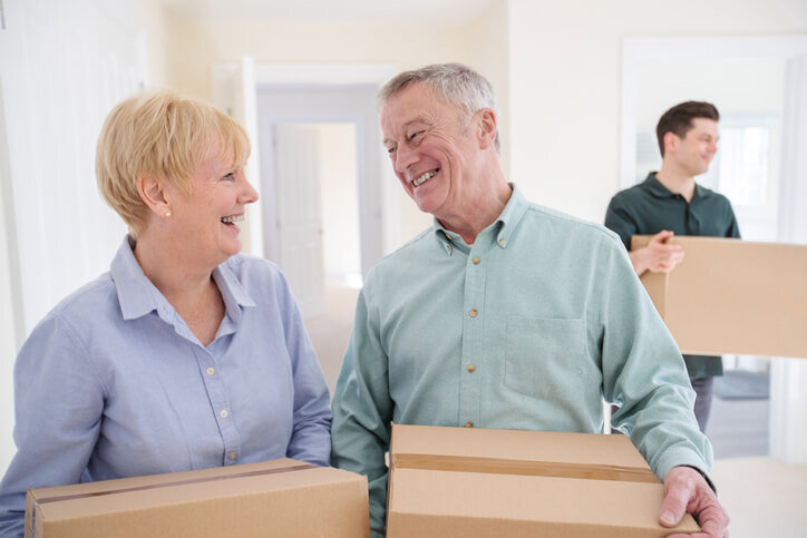 Senior-Couple-Downsizing-In-Retirement-Carrying-Boxes-Into-New-Home-sell-your-house-fast-golocalinvestor.com