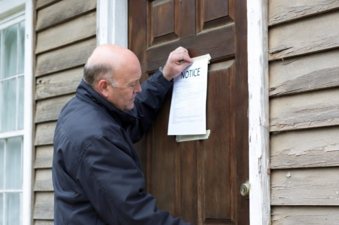 image of a tired landlord posting a notice on the door