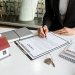 Real estate brokerage contracts for sale and rent with a house on the table in the office.