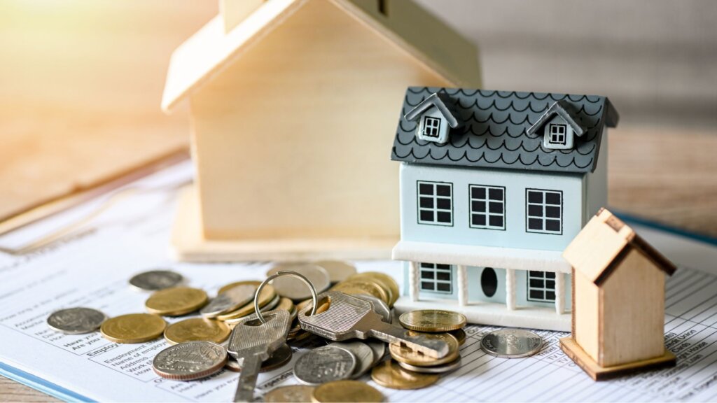 A miniature house model and a bunch of coins on a table