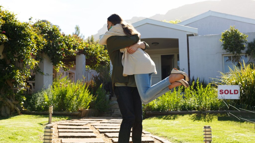 A couple celebrating with a house in the background