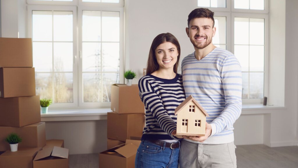 A couple holding a miniature house on their hands