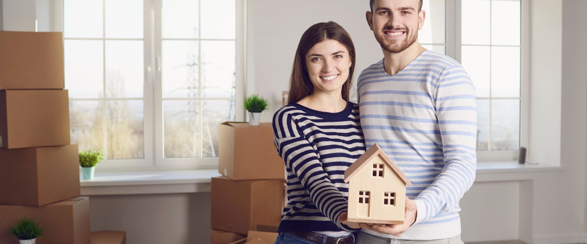 A couple holding a miniature house on their hands