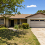 California ranch-style home with deferred maintenance including faded stucco, aging roof, overgrown landscaping, and cracked driveway — the type of as-is property cash home buyers in California purchase without requiring repairs.