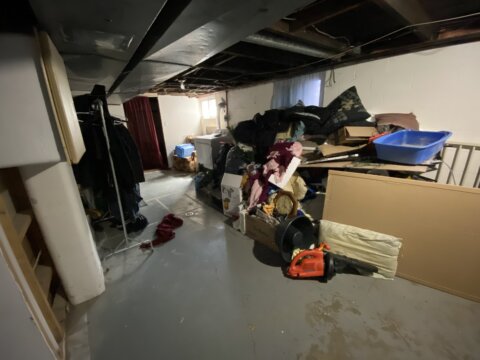 Cluttered basement with exposed wooden ceiling beams