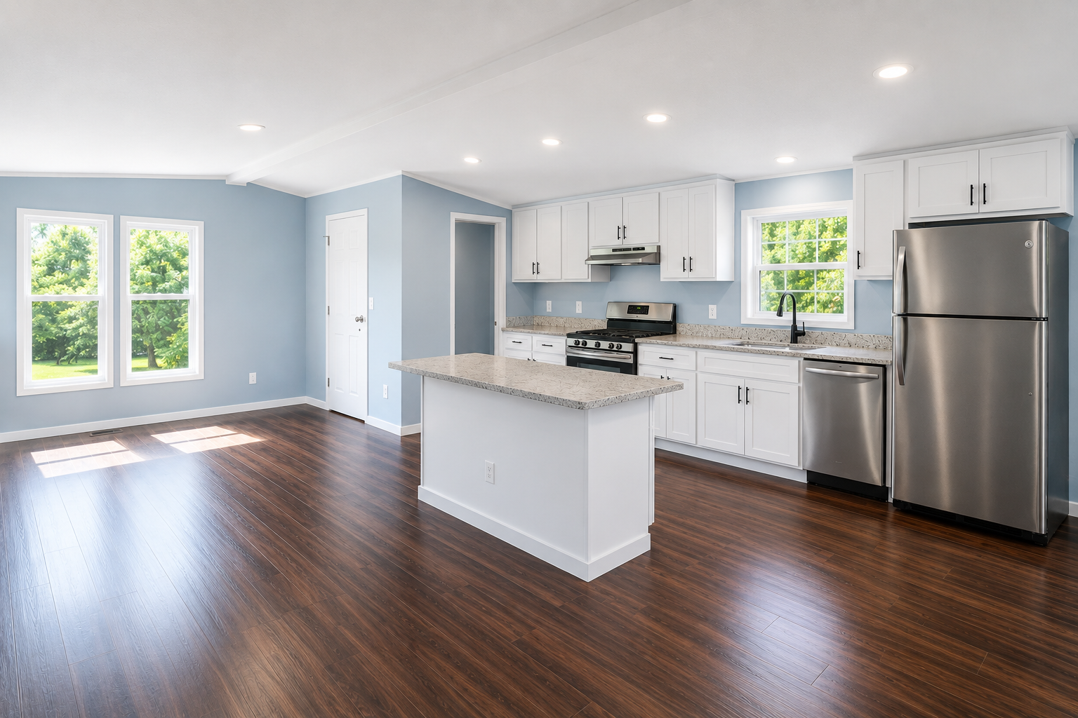 Open-concept renovated manufactured home interior with white cabinets, stainless steel appliances, and spacious living area.