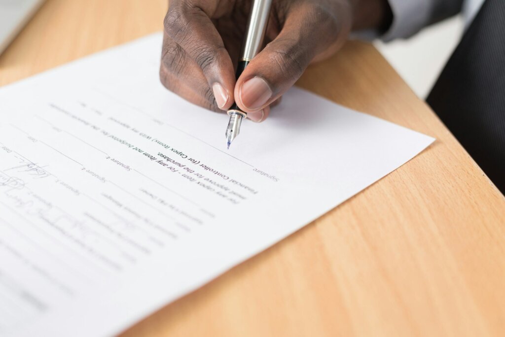 A person signing paperwork at a table