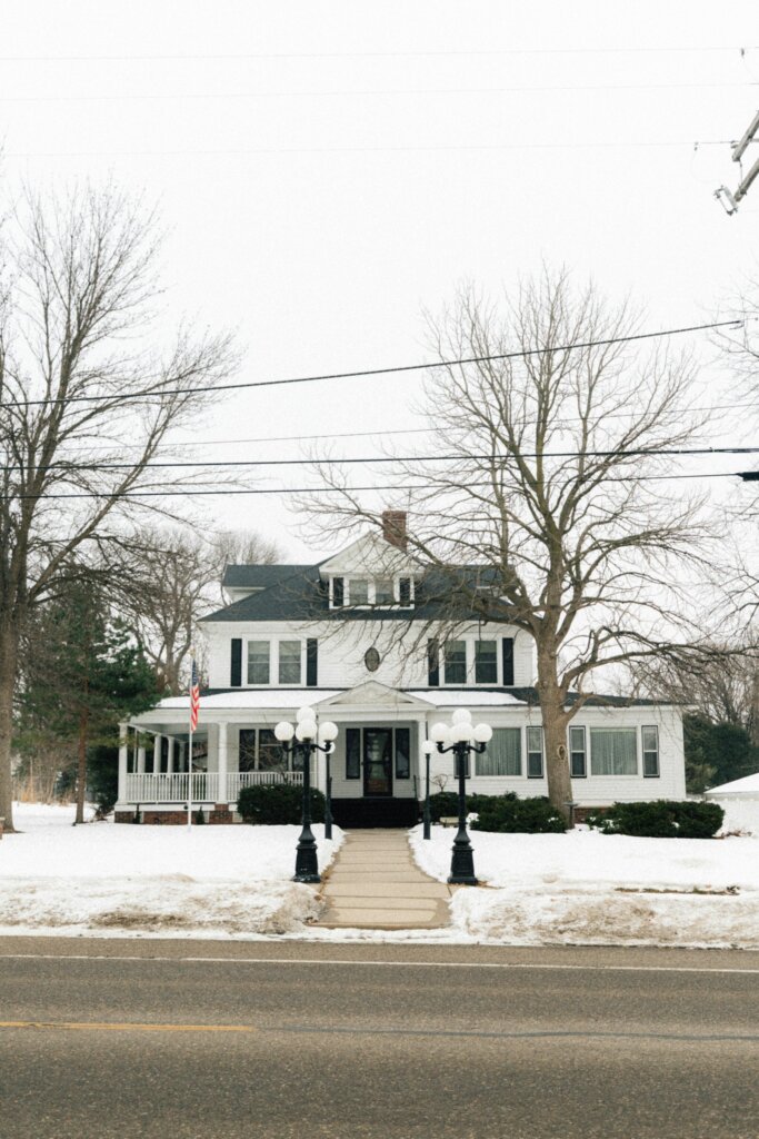 White house with a front porch on a snowy day