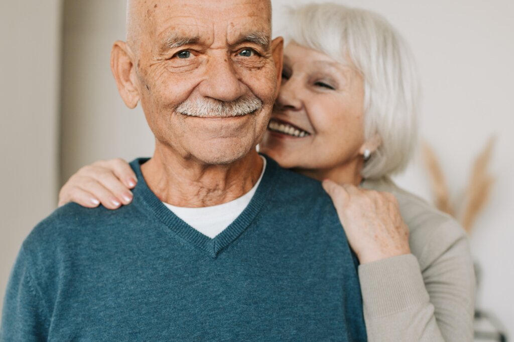 Elderly couple smiling after selling their house that needed repairs to move away from the busy city during retirement. They sold to a cash investor.