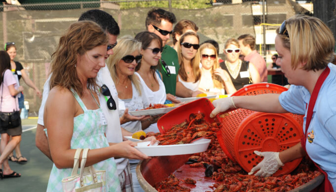 Picture of the Crawfish and Music Festival in Spring, Texas. There is a line of people getting served lots of crawfish on big trays.